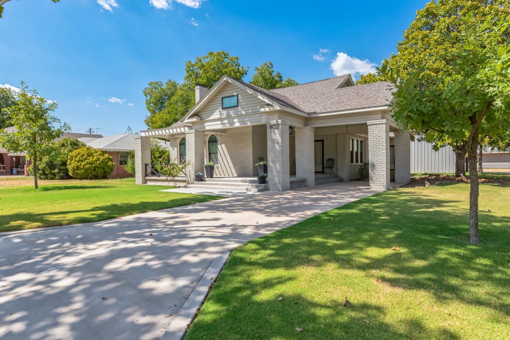 Greige brick home exterior with concrete driveway and stone walkway.