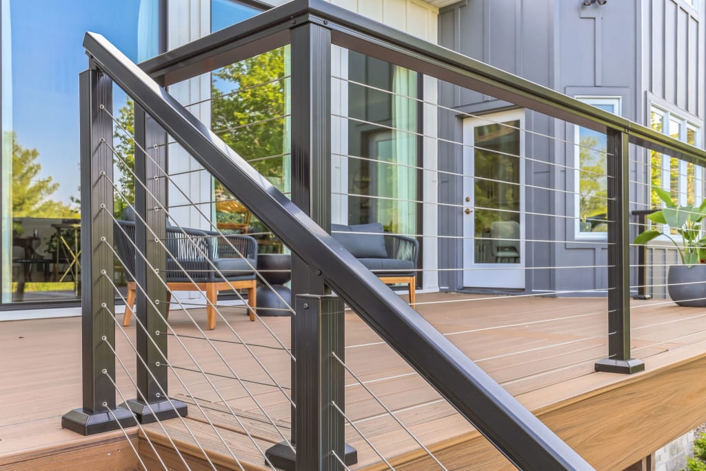 A close up of a the back of a home with a deck and cable railing
