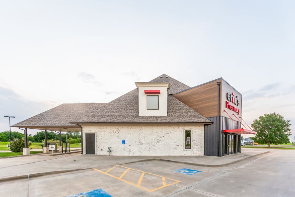 Commercial pharmacy exterior with wood and metal cladding and a bold color palette.