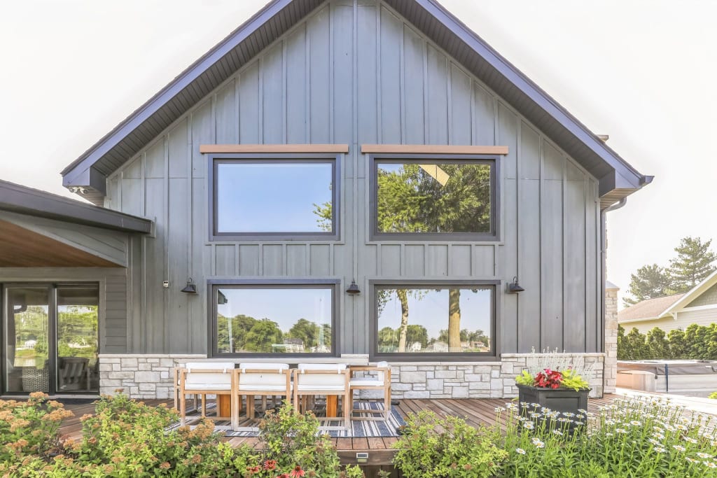 A home with dark siding and a deck with an outdoor dining table on it