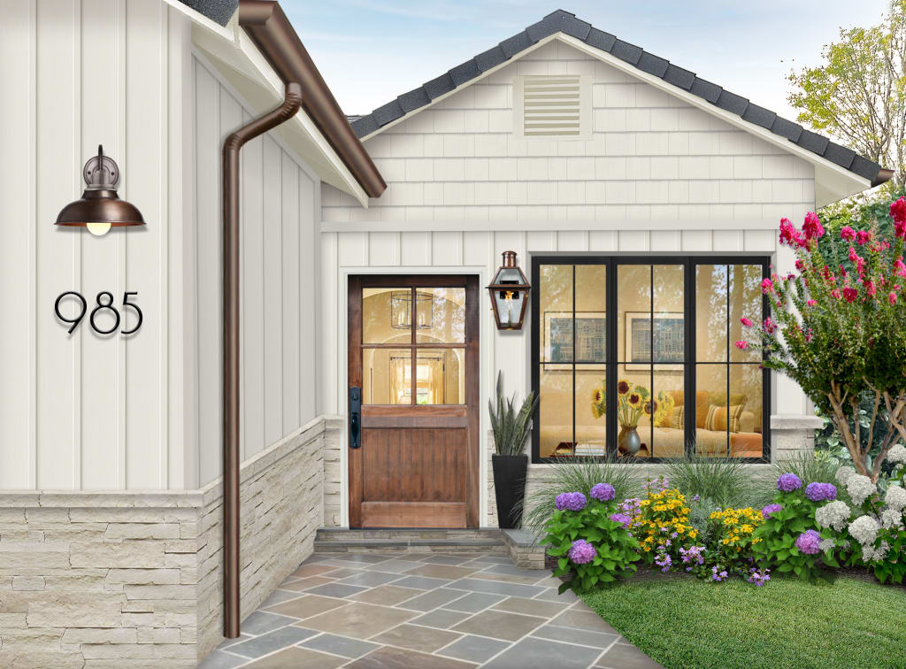 Exterior virtual renovation that zooms in on the entryway of home. With a stone walkway and lush greenery and colorful hydrangeas, the white home has black trim around the large front window. The door is wood, and there are elements of copper. The siding is painted Seapearl by Benjamin Moore on the siding and trim.
