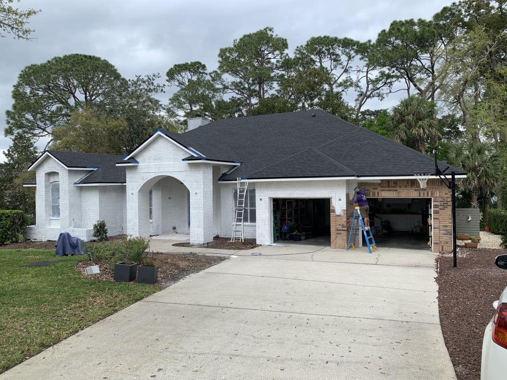 A photo of a half-painted brick home