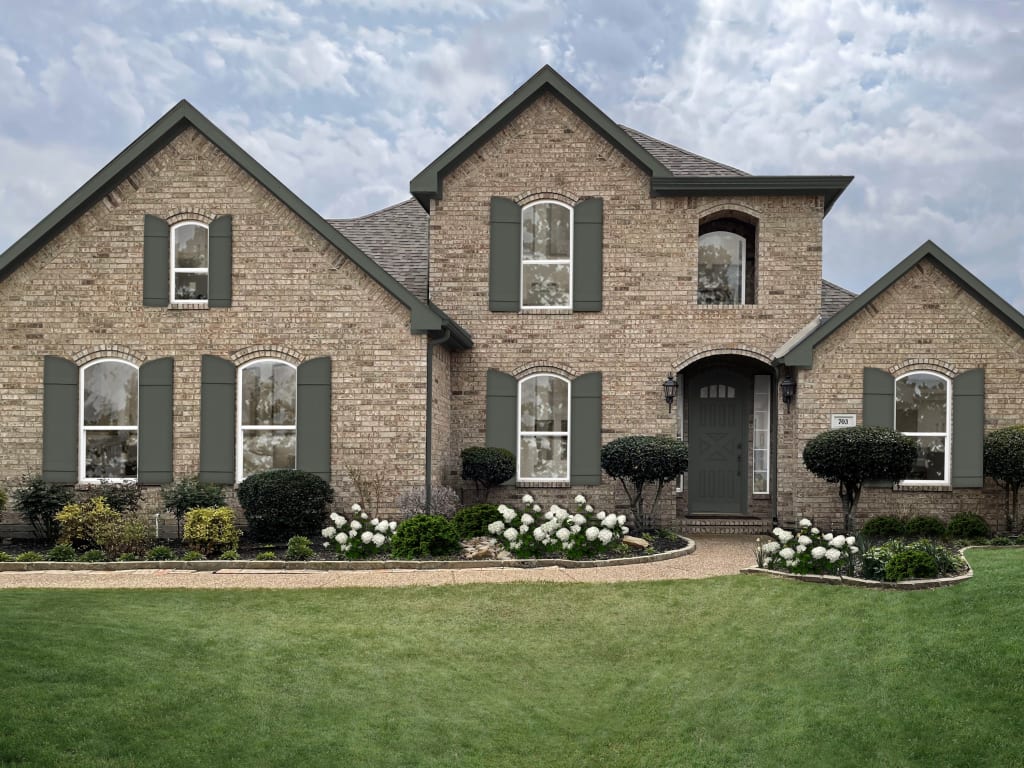 Tan and beige brick home with muted green shutters, and white trim