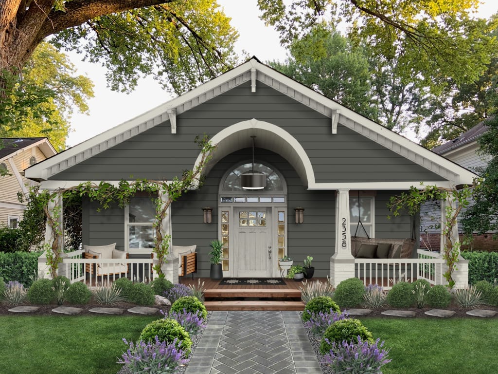 Dark green cottage with ivy wrapped porch, white trim, and arched portico featuring one of our Benjamin Moore exterior paint colors 2024