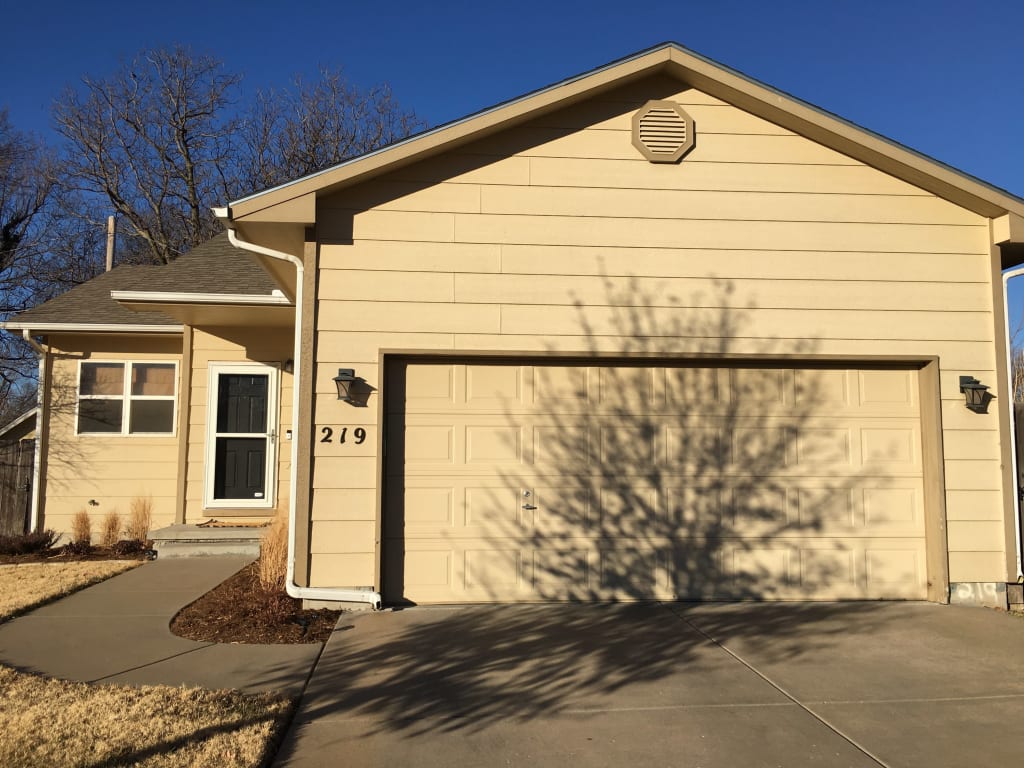 A photo of a home with horizontal siding and a front load garage