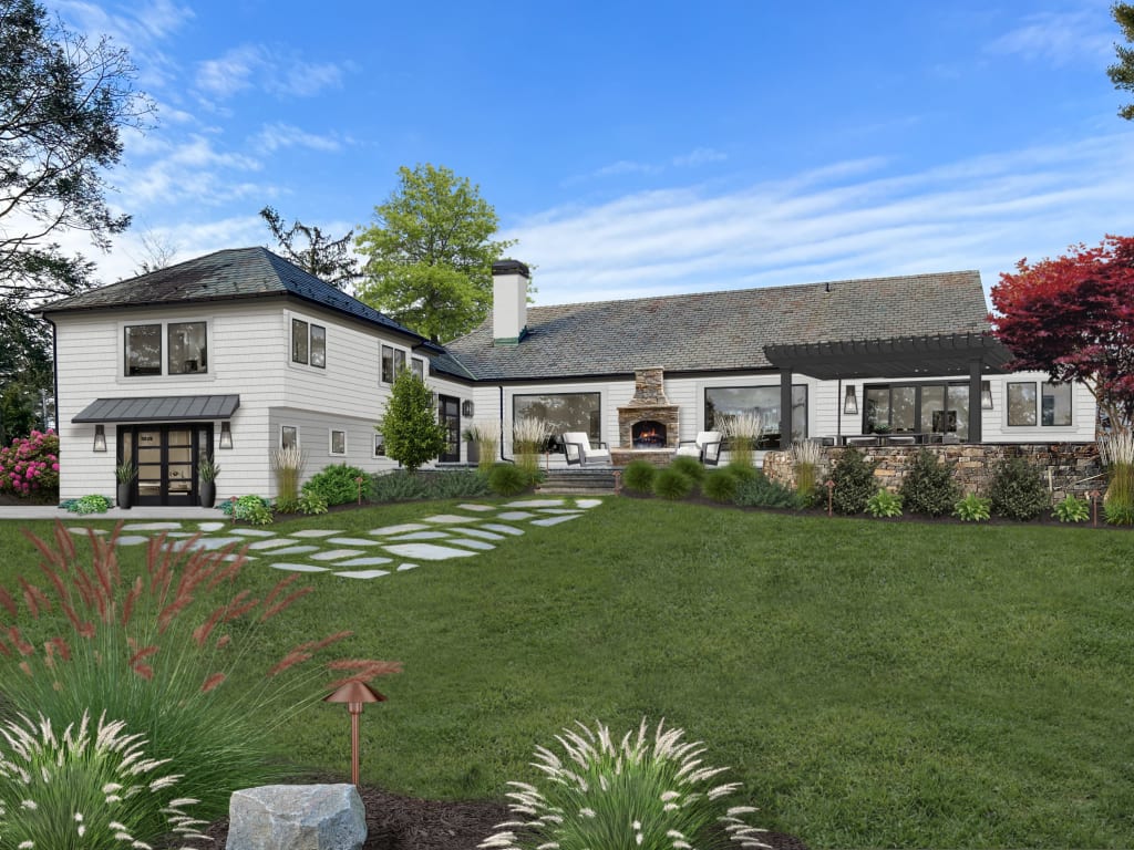 Backyard of a home with lush landscaping, an outdoor fireplace and lounge seating.