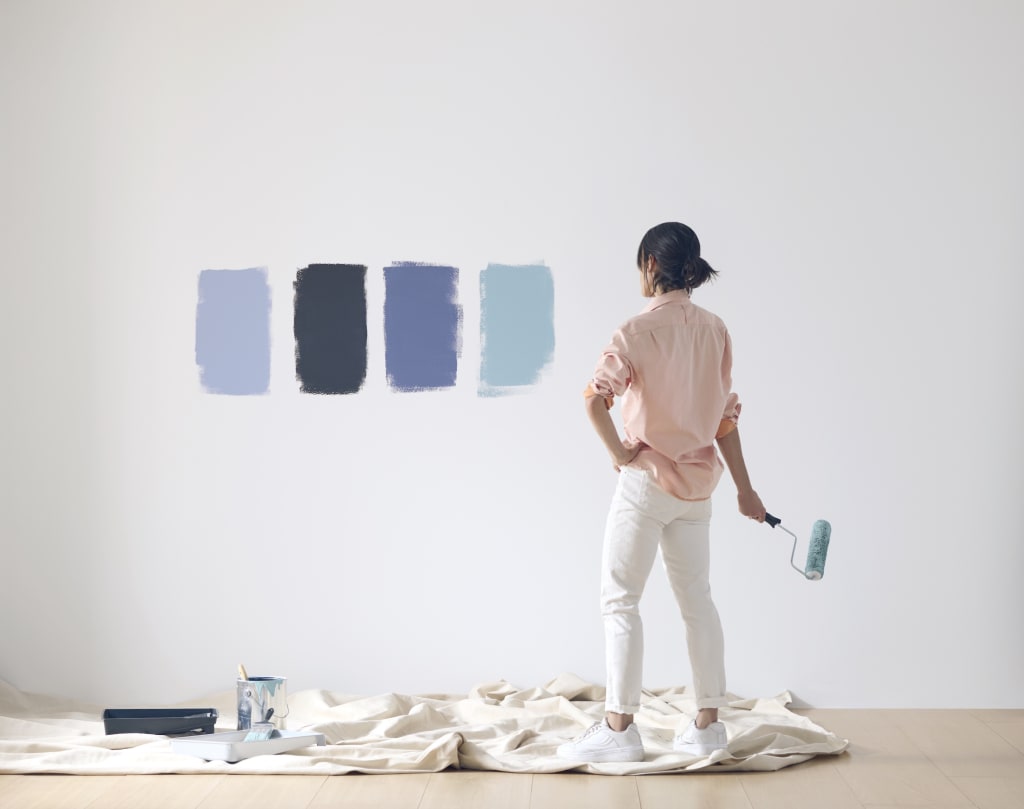A woman testing paint samples on her wall