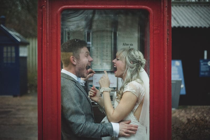 a married couple laughing in an old phone booth