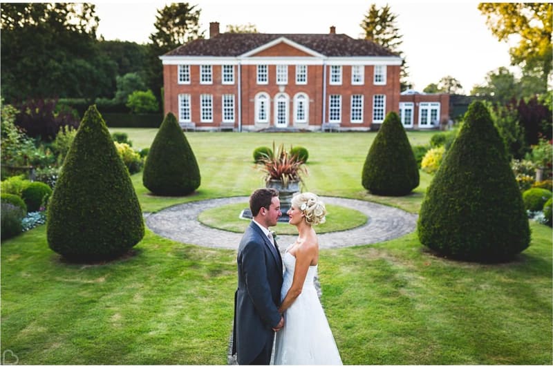 newlyweds pose in front of hockering house a country wedding venue in the uk