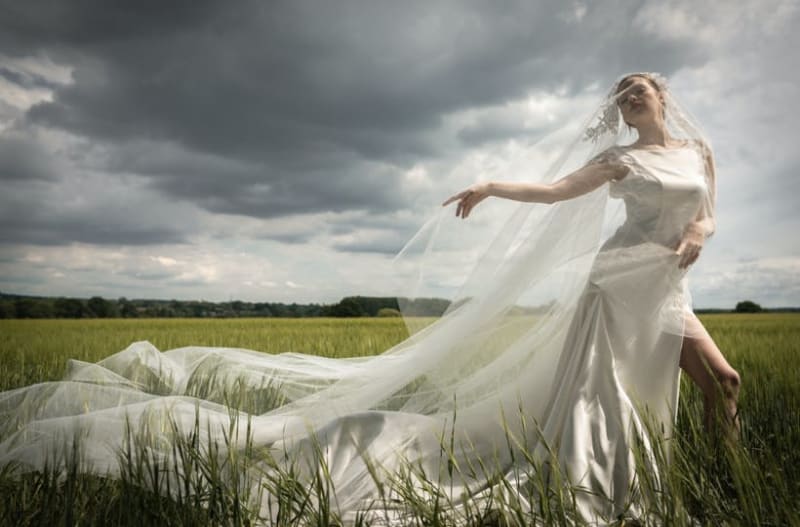 Bride walking in field wearing re-use wedding dress