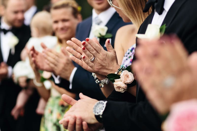 Wedding guests celebrating and clapping for the wedding couple