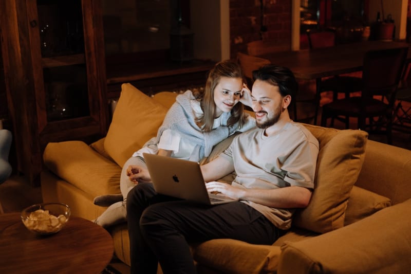 Couple sitting in living room with laptop 