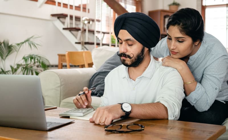 Engaged couple at home looking at saving money by browsing wedding venue virtual tours at home