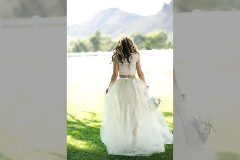 bridebook.co.uk bride walking in a field in a two piece wedding outfit