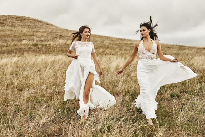 Bridebook.co.uk two brides in wedding dresses running in field