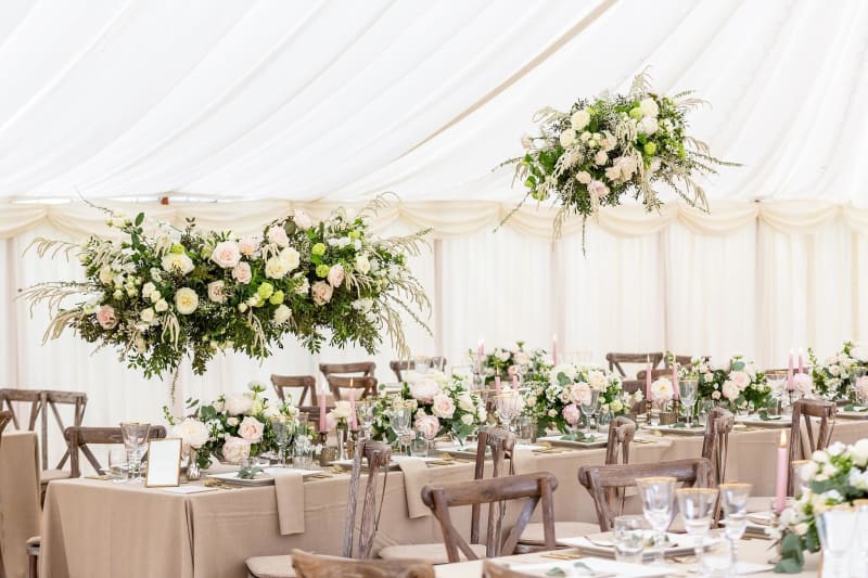 Tables set up and decorated with flowers for a wedding reception under a marquee.