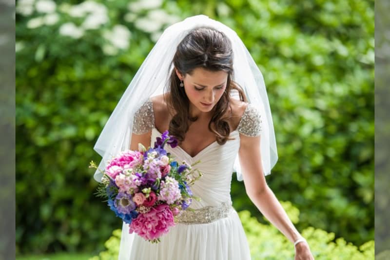 Bridebook.co.uk- bride in an embellished dress holding her bouquet