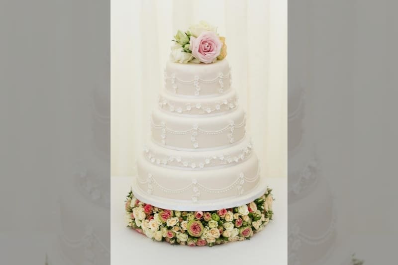 Bridebook.co.uk- five tier white wedding cake topped up with roses