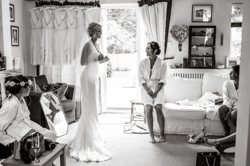 www.bridebook.co.uk bride in her dress as bridesmaid looks on smiling