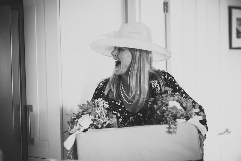 Bridebook.co.uk- mother of the bride laughing and carrying a box of flowers