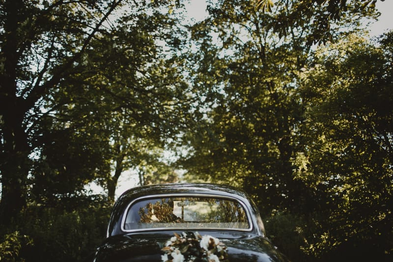 Bridebook.co.uk Vintage car just married under trees