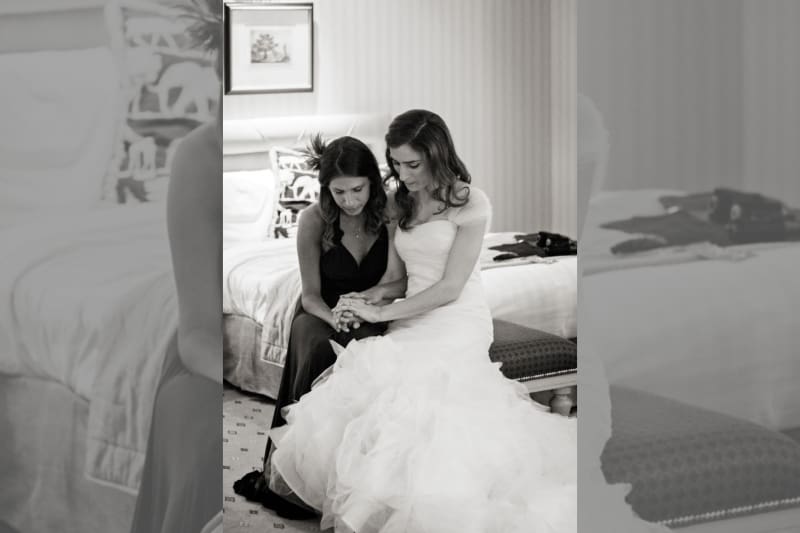 Bridebook.co.uk- bride and maid of honour sitting down and holding hands