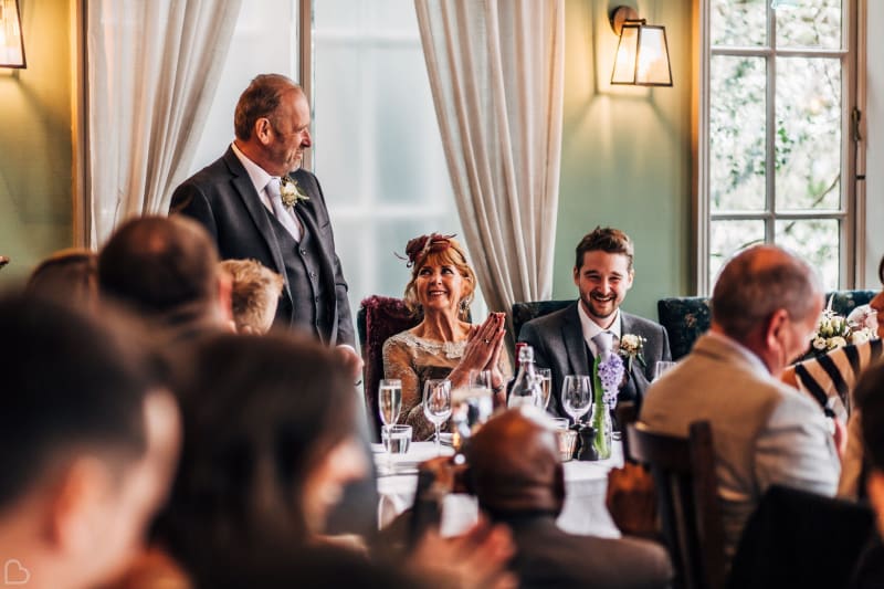 Dad giving his wedding speech as guests laugh.