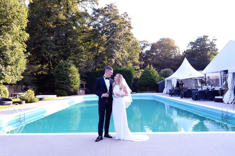 Newlyweds toast in front of the pool at The Kings Oak Hotel