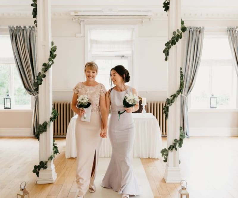 Brides walking down aisle with bouquets, smiling after ceremony
