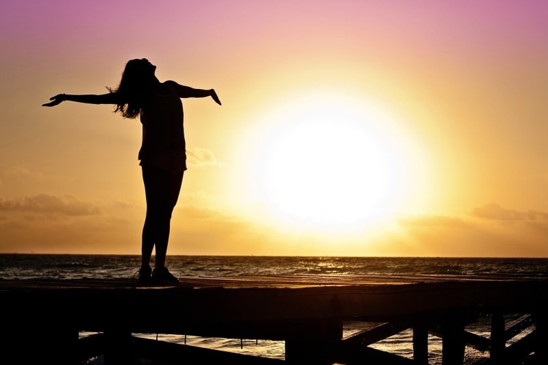 Woman being very happy by sea at sunet