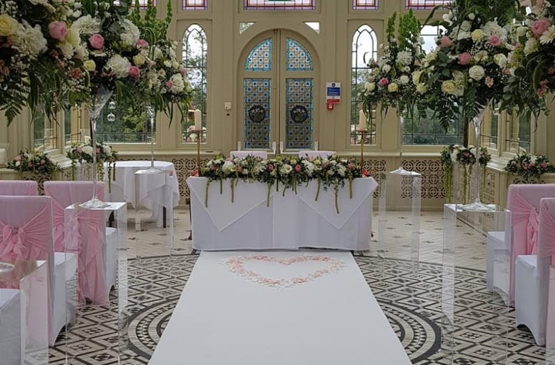 Lovely pink, white and yellow hanging flowers hung from ceiling of wedding venue above the wedding chairs