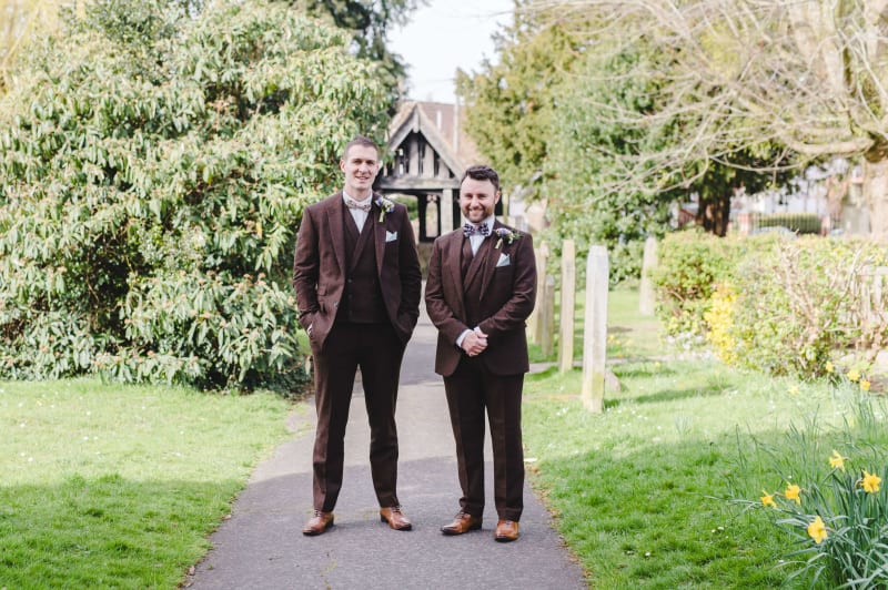 Adam and his best man standing outside the wedding venue in their wedding suits