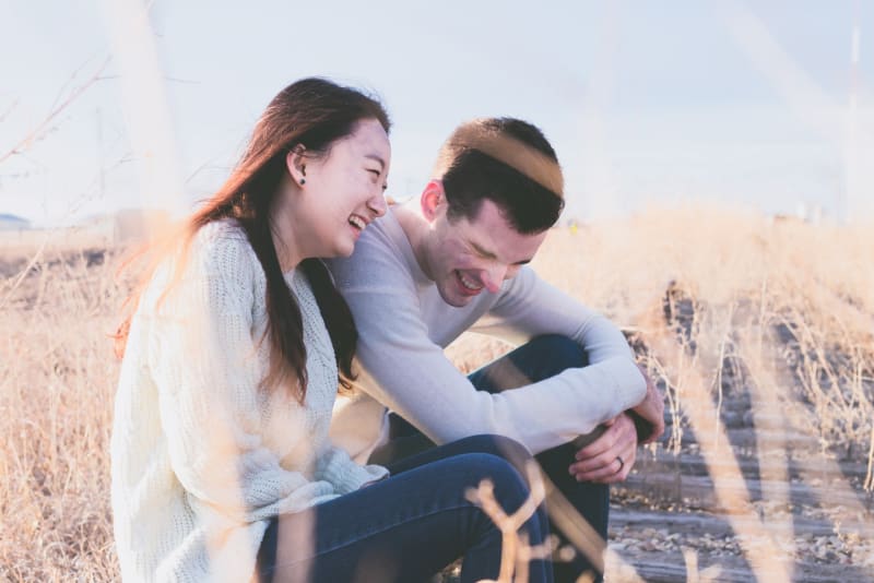 Couple in love sitting in field laughing