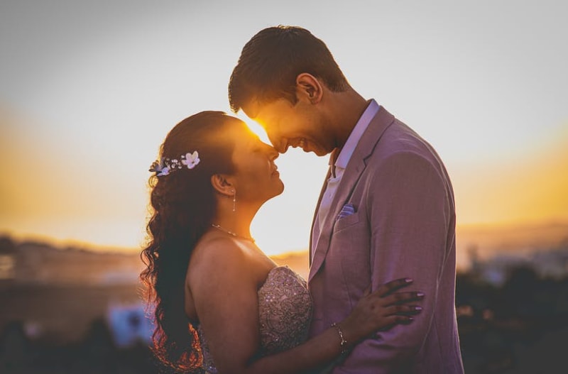 Married couple in love standing next to each other with sunset in background