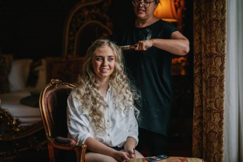 The bride gets her hair done by the hairdresser.