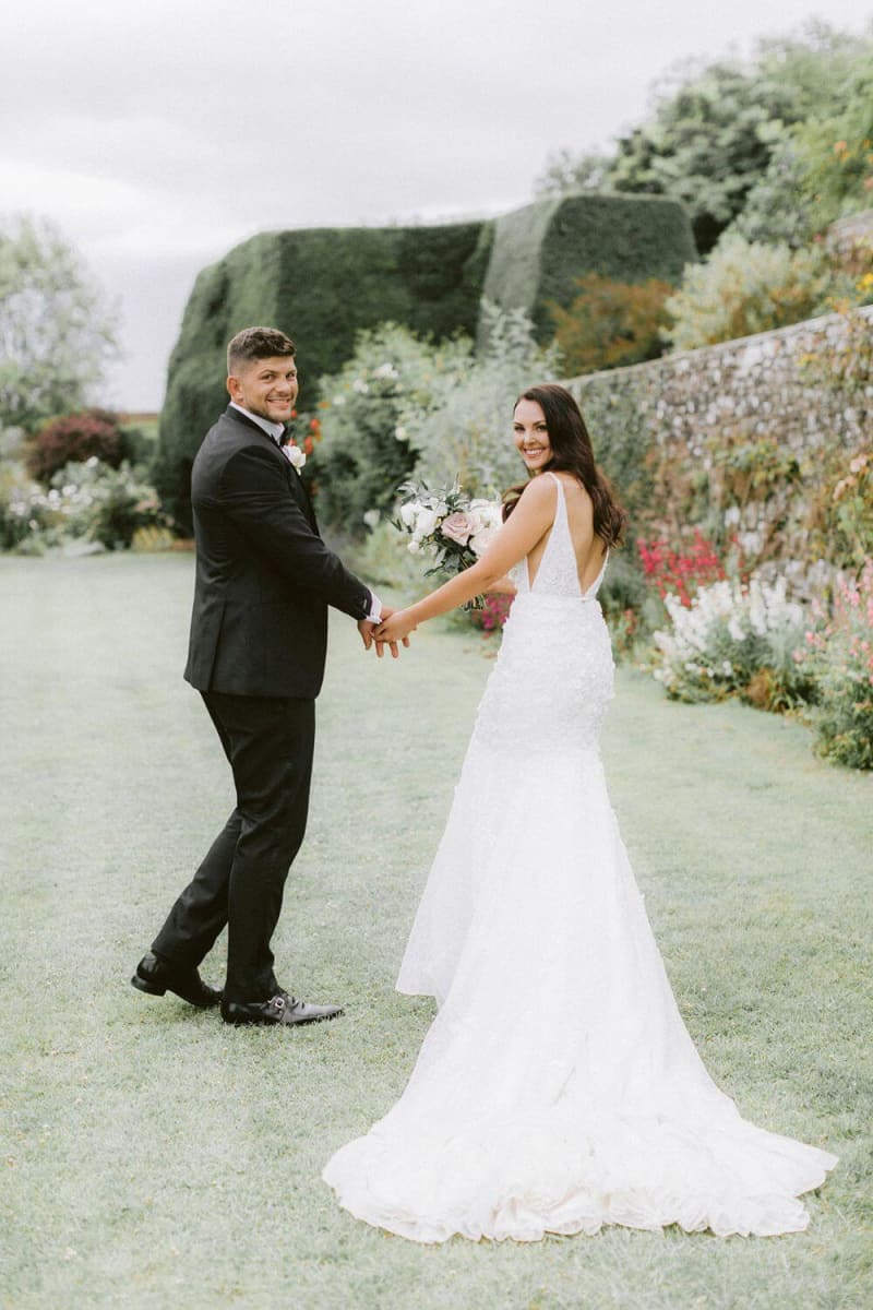 The bride and groom holding hands and smiling.