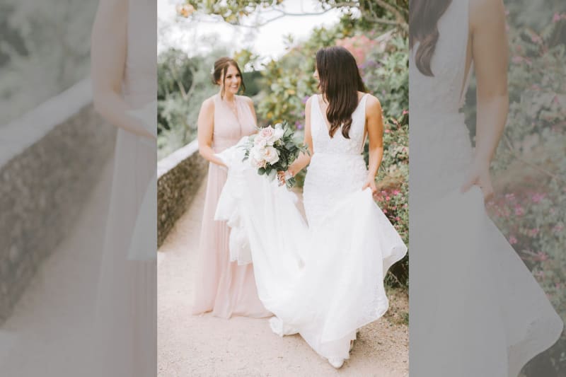 The bridesmaid holds the bride's dress.
