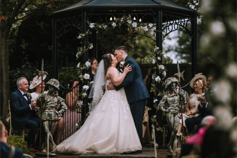 The bride and groom kiss under the gazebo.