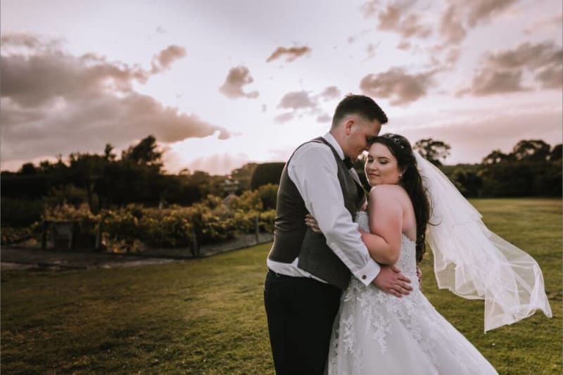The bride and groom embrace outside.