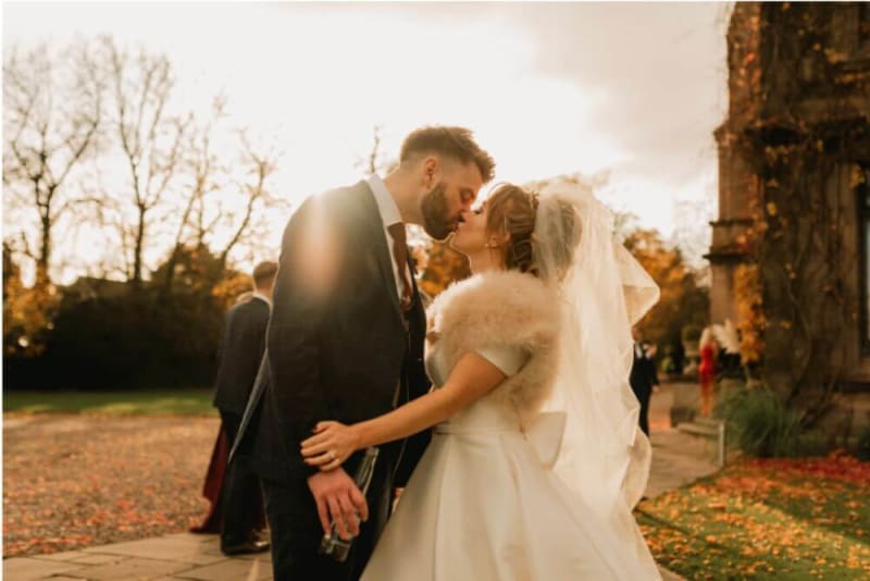 The bride and groom kiss outside.