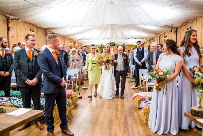 The bride walks down the aisle with her parents.