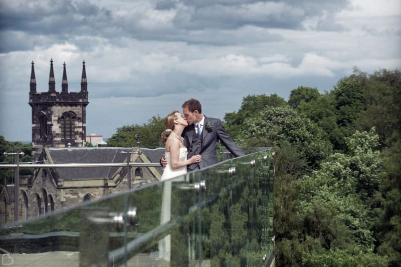 newlyweds kiss on the balcony of The Glasshouse Hotel.