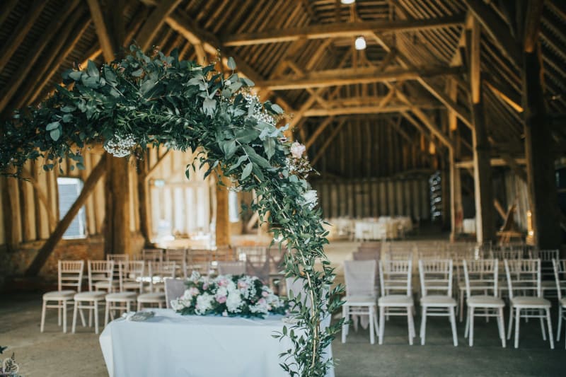 barn decorated for wedding ceremony with green arch.