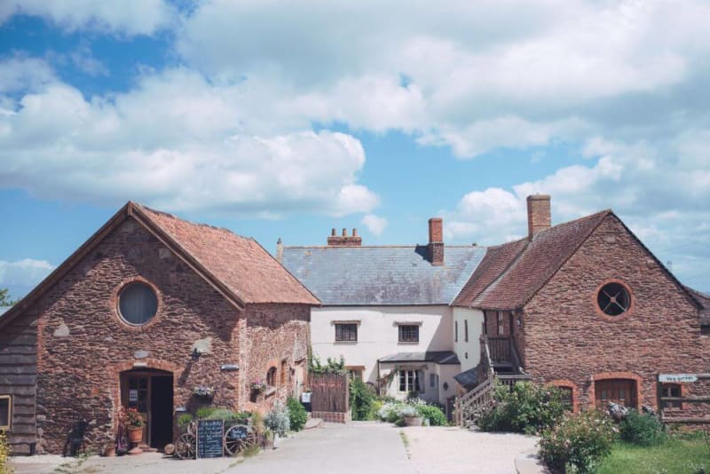 A shot of Huntstile Farm from the outside. The building has a rustic look to it, with stone walls.