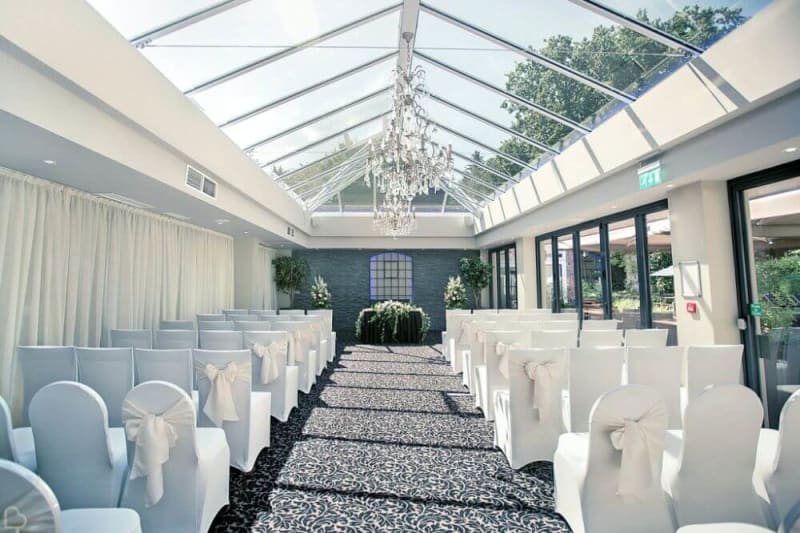 Inside the glass house. White chais are facing the ceremony area.