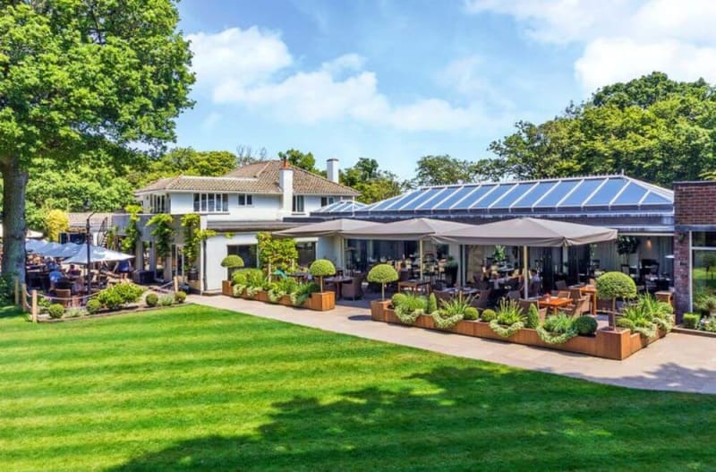 A white house next to a glass house in the garden.