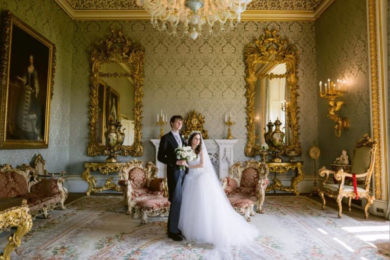 Bride and groom posing for a photo in an elegant room.