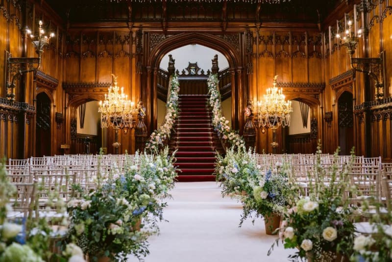 A grand inside staircase and chairs decorated with flowers for a wedding ceremony. 