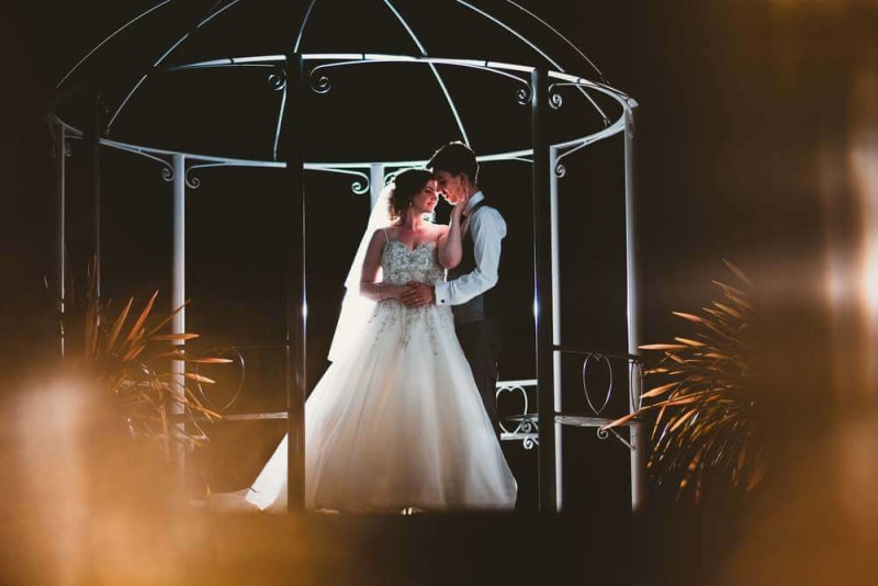 At night, a couple embraces under the wedding gazebo.