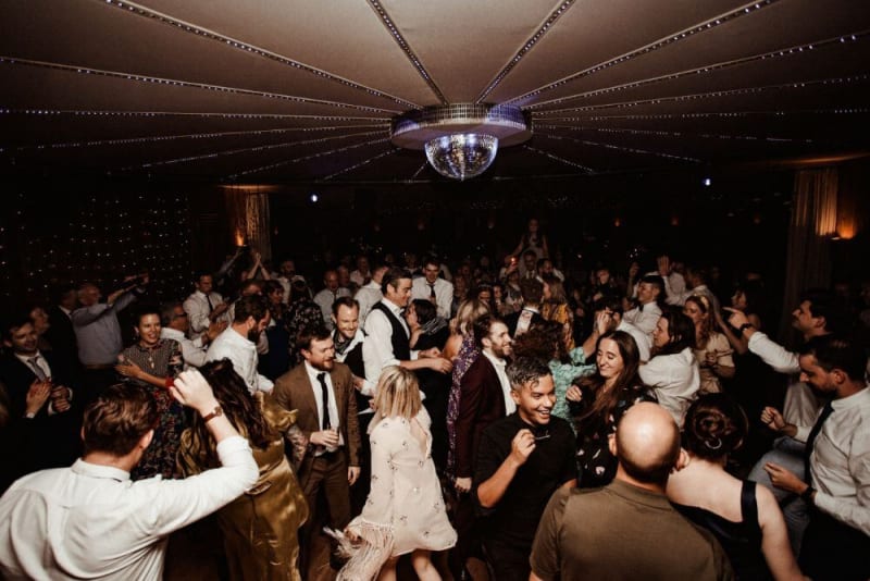 Lots of wedding guests dancing under a disco ball.